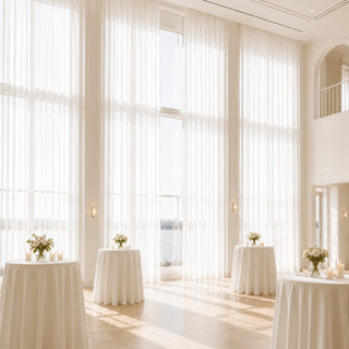 Elegant white wedding reception venue with tall windows and floral table decor