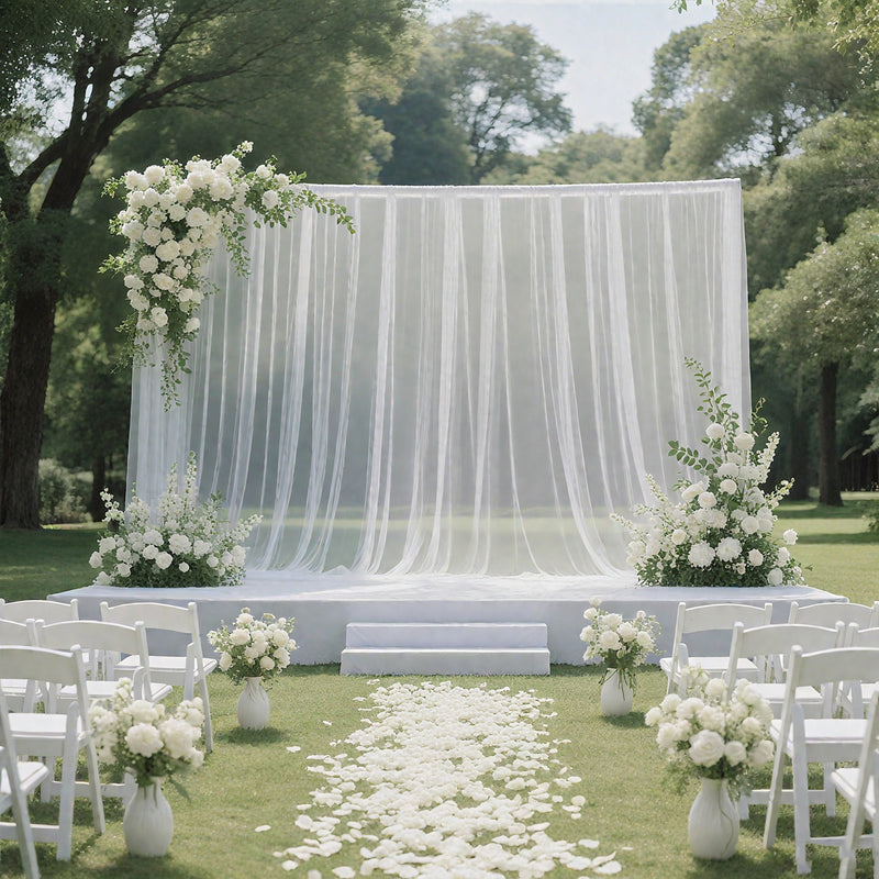 White draped wedding backdrop with floral arrangements