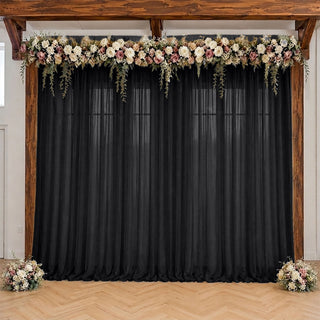 Wedding backdrop with black drapes, floral garland, and wooden frame