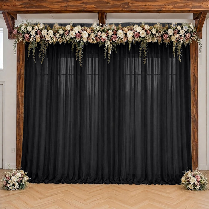 Wedding backdrop with black drapes, floral garland, and wooden frame