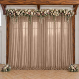 Rustic wedding backdrop with floral garland, beige drapes, and wooden arch