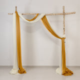 Rustic wooden arch draped with white and gold fabric on a plain wall