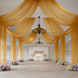 Elegant wedding hall with gold drapery, chandeliers, and floral stage decor