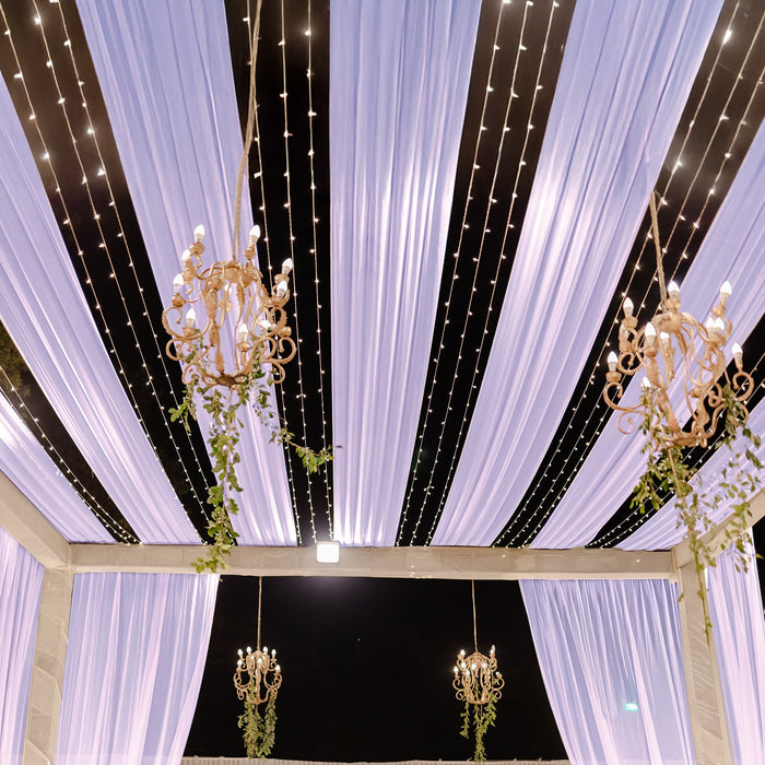 Elegant event ceiling draped with lavender fabric and twinkling lights.