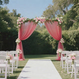 Pink floral wedding arch with white chairs and aisle in a garden setting