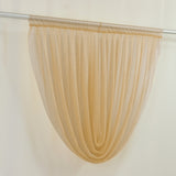 Sheer beige curtain panel hanging on a rod against a cream wall