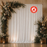 Elegant wedding backdrop with white drapery, floral arch, and lanterns