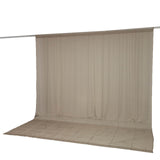 Beige sheer curtain panel hanging on a rod with matching floor drape
