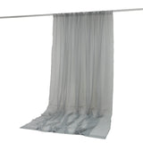 Light gray sheer curtain hanging on a rod with a pooled draped hem
