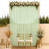 Elegant wedding backdrop with mint drapes, white roses, gold chairs, and candles
