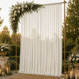 Elegant outdoor wedding backdrop with white drapes, roses, greenery, and lanterns