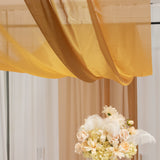Elegant floral centerpiece with soft fabric drapery above.