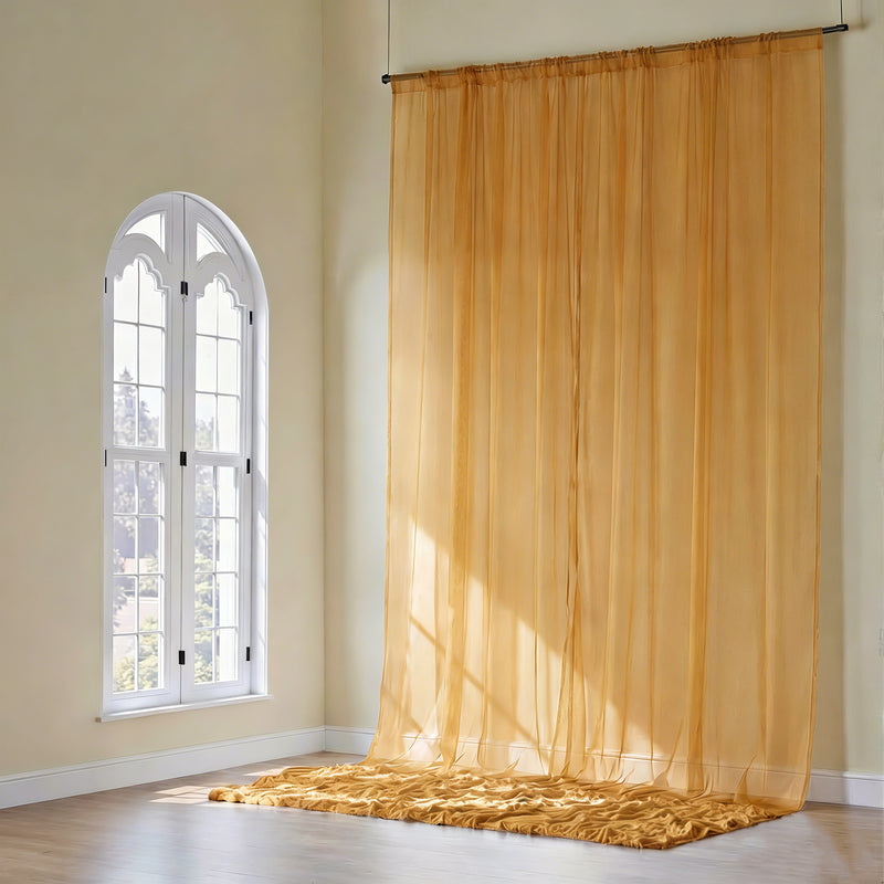 Gold sheer backdrop curtain hanging by a window