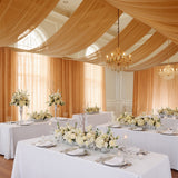 Elegant wedding reception with floral centerpieces and draped fabric decor.