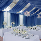Elegant wedding reception setup with blue drapery and floral centerpieces.