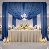 Elegant wedding reception setup with blue drapes, floral arrangements, and candlelight.
