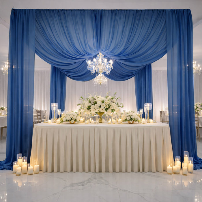 Elegant wedding reception setup with blue drapes, floral arrangements, and candlelight.