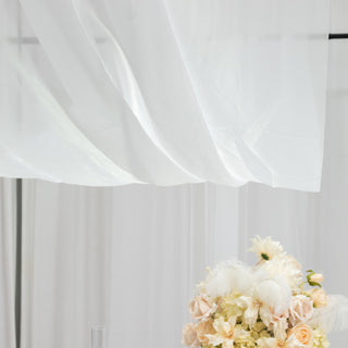 Delicate white fabric draping above a floral arrangement.
