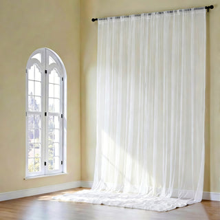 Sheer white curtains gently flowing in a bright, airy room.