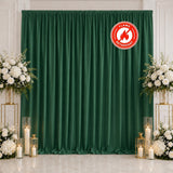 Elegant green curtain wedding backdrop with white floral arrangements and candles