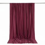 Burgundy satin curtain draped on rod, elegant luxury fabric backdrop