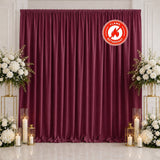 Elegant burgundy flame-retardant event backdrop with floral arrangements and candles
