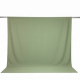Light sage green seamless fabric backdrop hanging on a studio rod