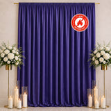 Purple event curtain backdrop with white floral arrangements, candles, and flame retardant badge