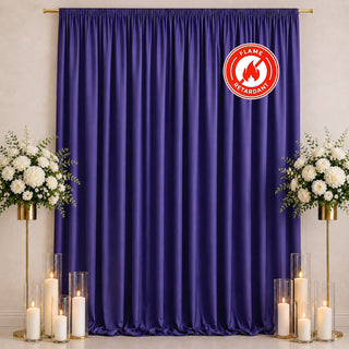 Purple event curtain backdrop with white floral arrangements, candles, and flame retardant badge
