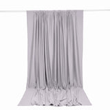 Light gray draped curtain panel hanging on a rod, elegant fabric backdrop