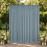 Outdoor wedding backdrop with blue draped curtain and floral arrangements