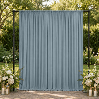 Outdoor wedding backdrop with blue draped curtain and floral arrangements