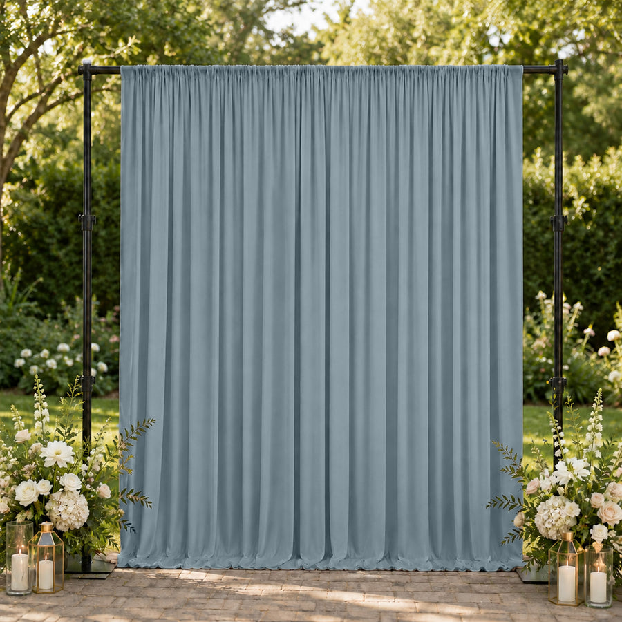 Outdoor wedding backdrop with blue draped curtain and floral arrangements