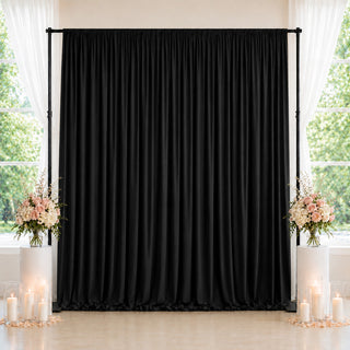 Black wedding backdrop with floral arrangements and candles by windows
