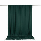 Dark green draped curtain on a silver rod against a white background