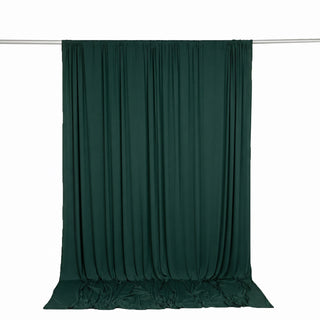 Dark green draped curtain on a silver rod against a white background