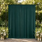 Elegant green outdoor wedding backdrop with floral arrangements and candles