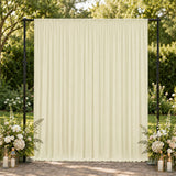Cream draped wedding backdrop with floral arrangements and lanterns outdoors