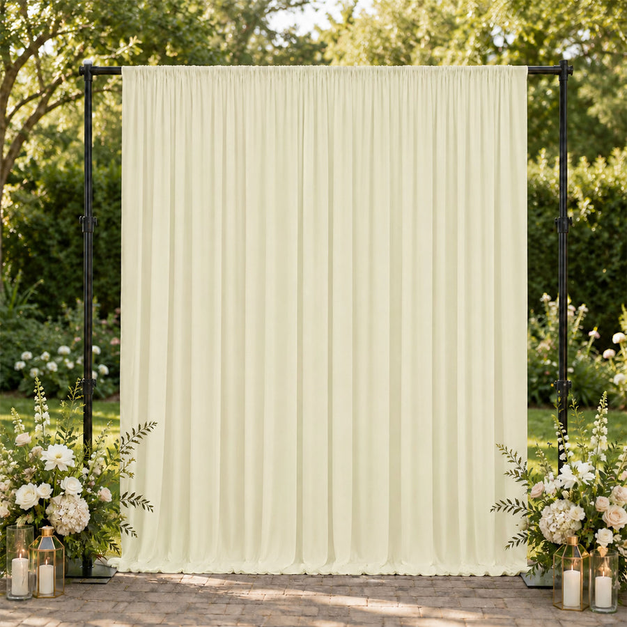 Cream draped wedding backdrop with floral arrangements and lanterns outdoors