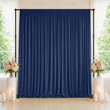 Navy blue draped wedding backdrop with floral arrangements and candles