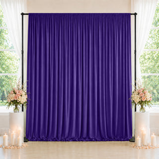 Purple draped backdrop with floral arrangements and candlelit wedding decor