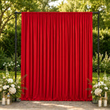Red event curtain backdrop with floral garden decor and lanterns outdoors