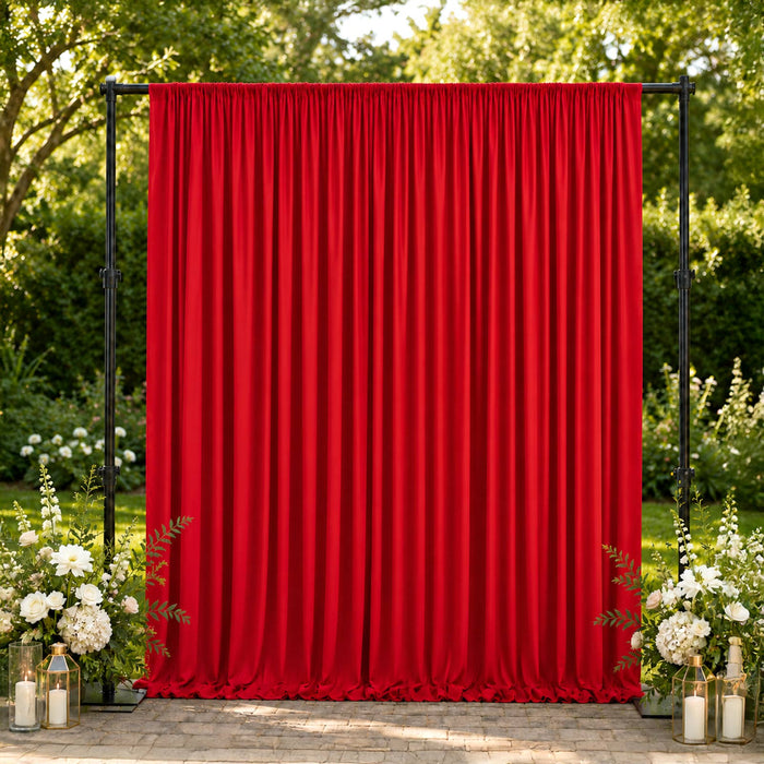 Red event curtain backdrop with floral garden decor and lanterns outdoors