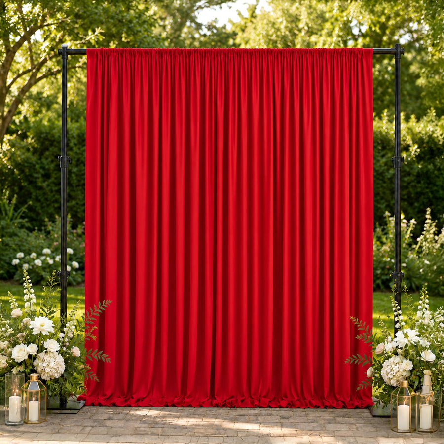 Red event curtain backdrop with floral garden decor and lanterns outdoors