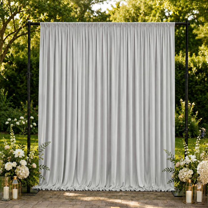 Outdoor wedding backdrop with white draped curtain and floral arrangements