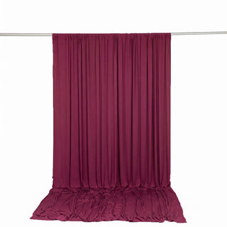 Burgundy draped fabric curtain backdrop on hanging rod
