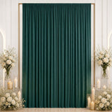 Elegant emerald green curtain backdrop with white floral arrangements and candles