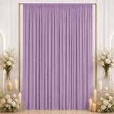 Lavender draped backdrop with white floral arrangements and candles
