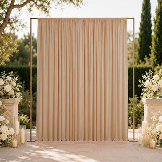 Elegant outdoor wedding backdrop with beige drapes and white floral arrangements