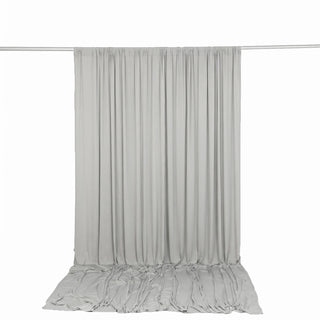 Light gray draped curtain backdrop on crossbar stand with pooled fabric